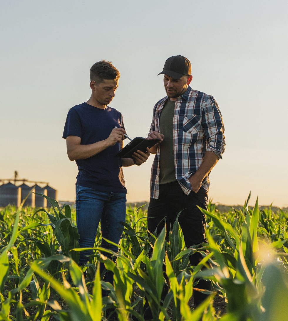 Nebraska farmers reviewing tablet data in cornfield, independent ag advice